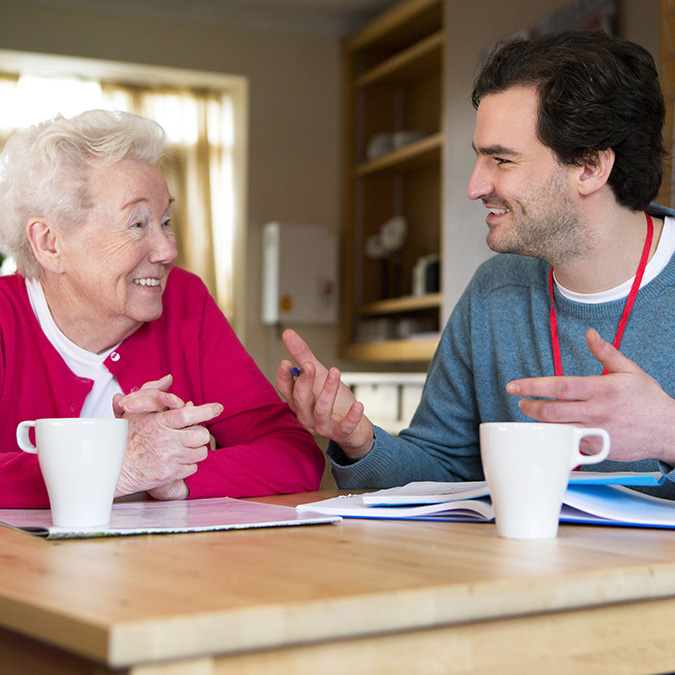 Friendly male volunteer assisting a senior woman with paperwork. companionship for elderly woman